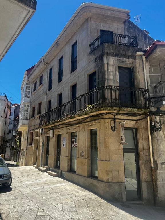 un antiguo edificio de piedra con balcón en una calle en Apartamentos Redondela - Centro histórico, en Redondela