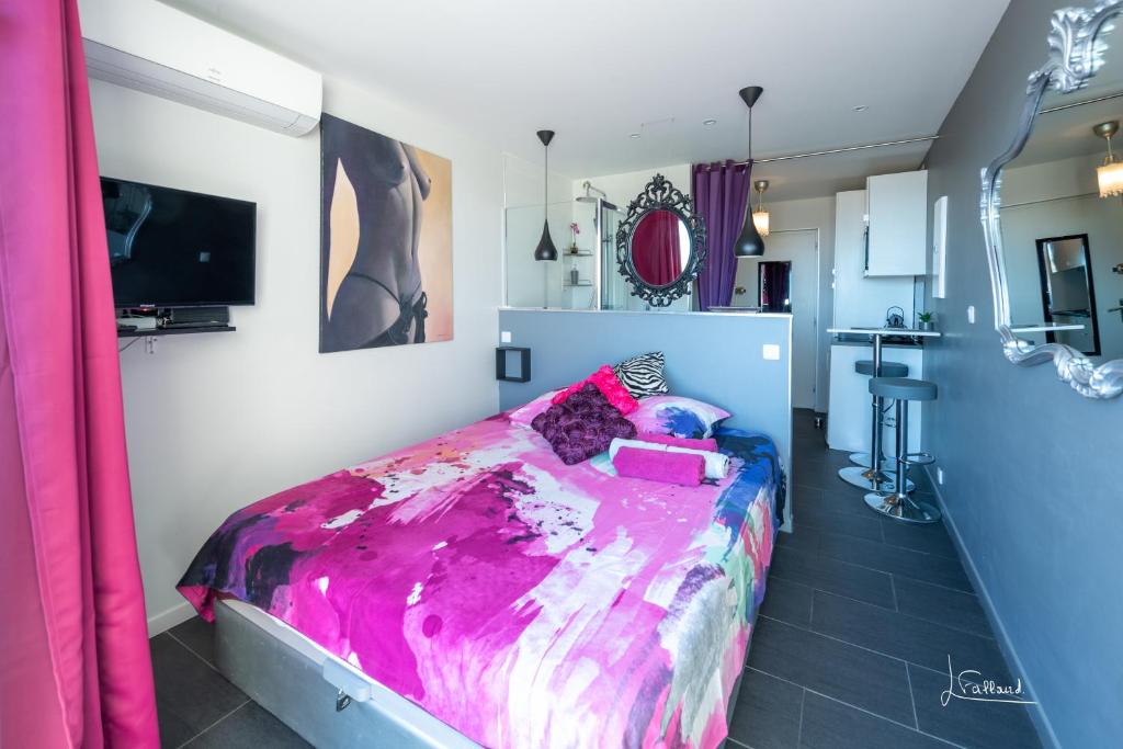une chambre avec un grand lit avec une couverture violette dans l'établissement Studio Glamour Naturiste, au Cap d'Agde