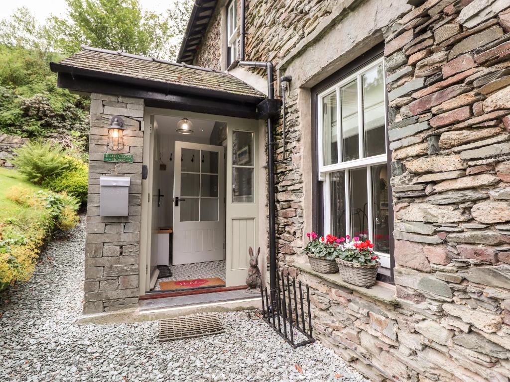 ein Steinhaus mit einer weißen Tür und Blumen in der Unterkunft Eller Close House in Ambleside