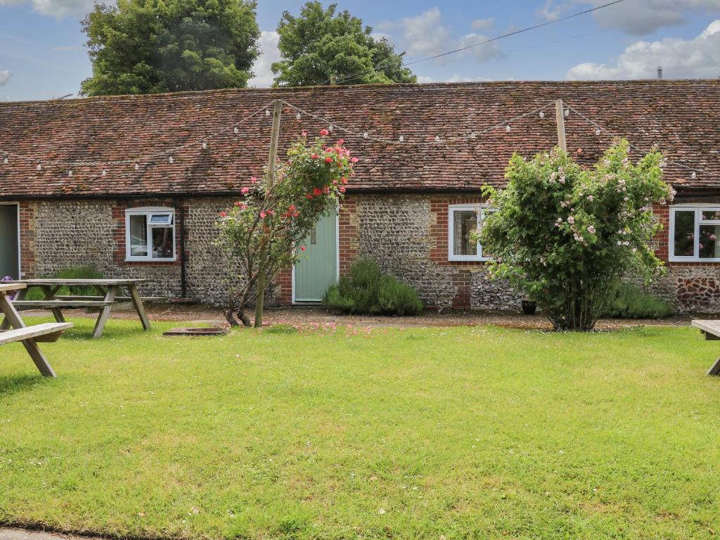 a brick cottage with a picnic table and a bench at Byre Cottage 4 in Pulborough