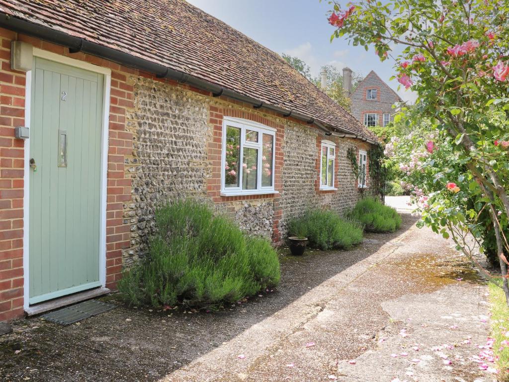 Una casa de ladrillo con una puerta verde. en Byre Cottage 2, en Pulborough