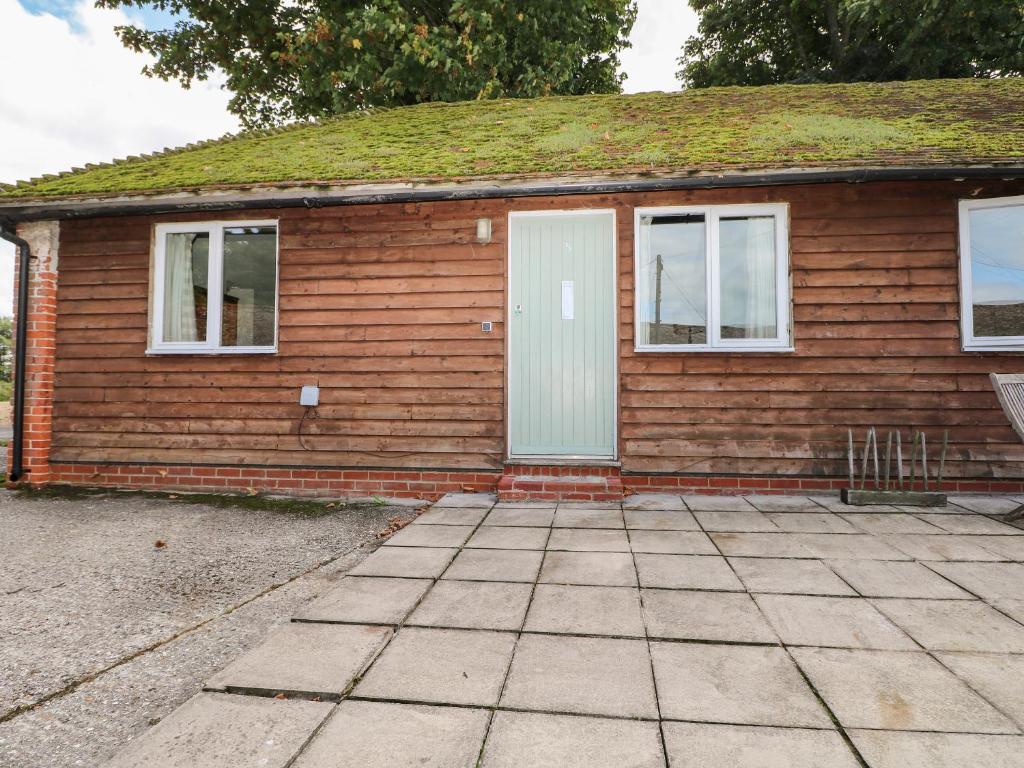 een klein huis met een witte deur en ramen bij Byre Cottage 5 in Pulborough