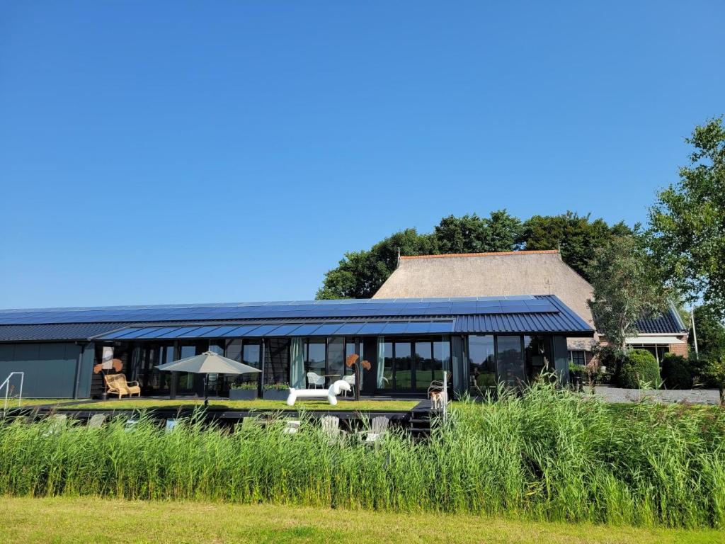 uma casa com um jardim de Inverno com um telhado em Hippe Schuur em Tietjerk