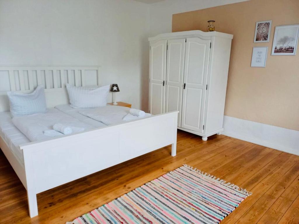 a bedroom with a white bed and a cabinet at Familienhof Müritz in Klein Plasten