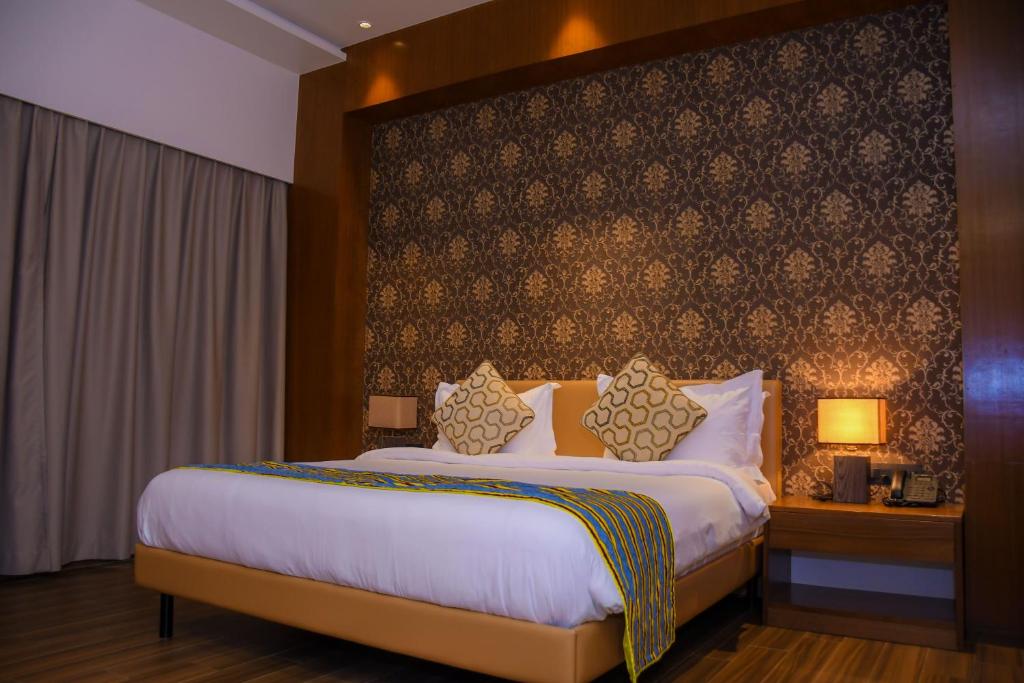 a hotel room with a large bed and a wall at AQUA INN Hotel in Kinshasa