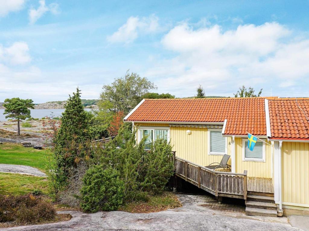 a yellow house with a wooden porch and a deck at 8 person holiday home in STRÖMSTAD in Strömstad