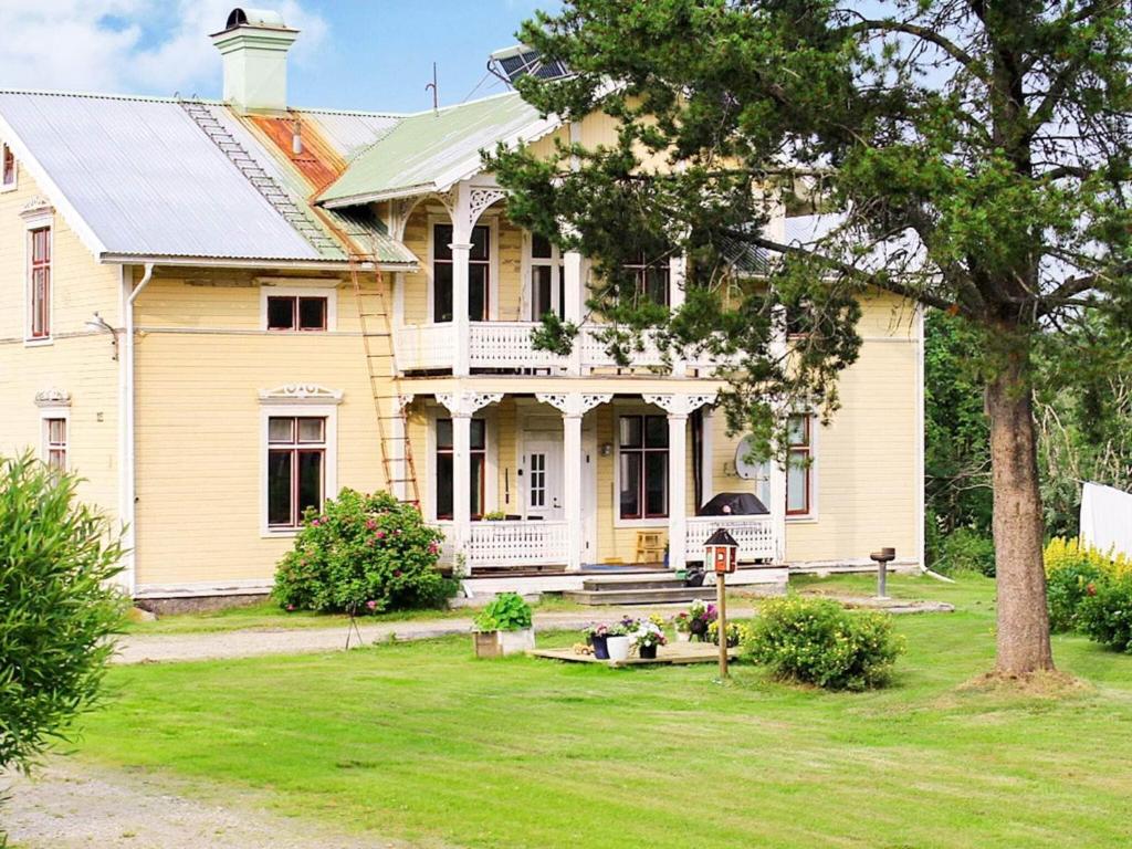 ein altes gelbes Haus mit einem Baum im Hof in der Unterkunft 9 person holiday home in K LARNE in Kälarne