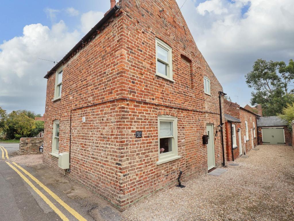 an old brick building on the side of a street at Printers Cottage in Alford