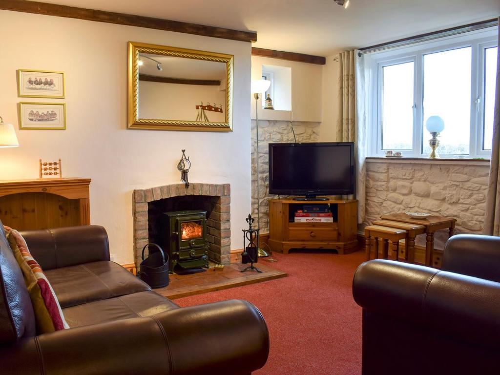 a living room with a fireplace and a television at Augustus Cottage in Rowlstone