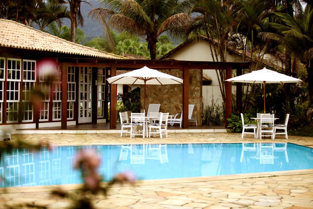 a resort with a pool with chairs and umbrellas at Villas De Paraty in Paraty