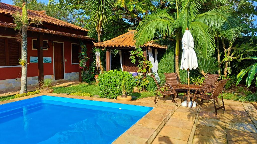 a house with a pool and a table and an umbrella at Pousada Casa da Aroeira in Búzios