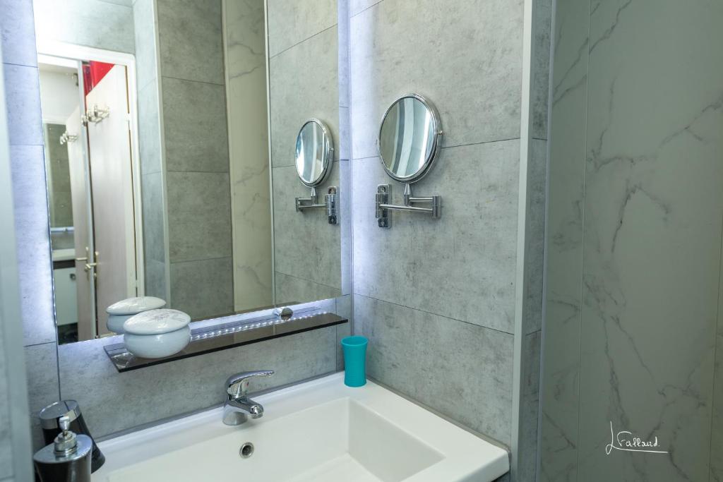 baño con lavabo y 2 espejos en Purple Secret Naturiste, en Cap d'Agde