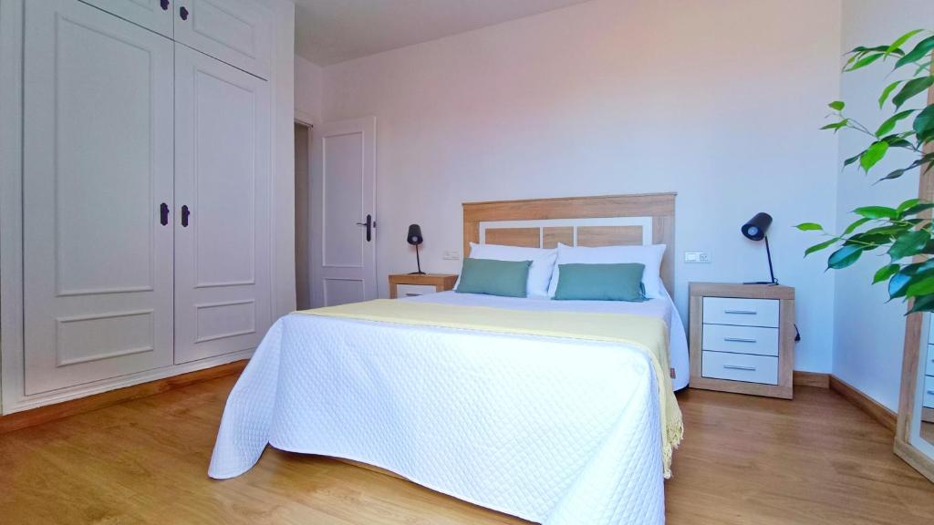 biała sypialnia z dużym białym łóżkiem z niebieskimi poduszkami w obiekcie Ático Deluxe Granada, Parking gratis y Terraza w mieście Armilla