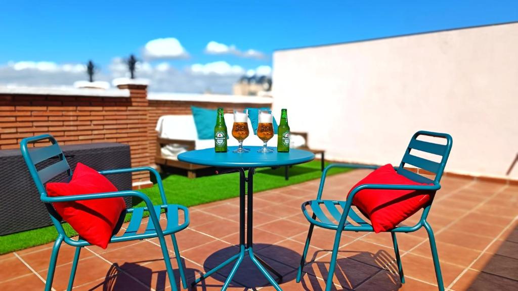 2 chaises et une table avec des boissons sur la terrasse dans l'établissement Ático Deluxe Granada, Parking gratis y Terraza, à Armilla