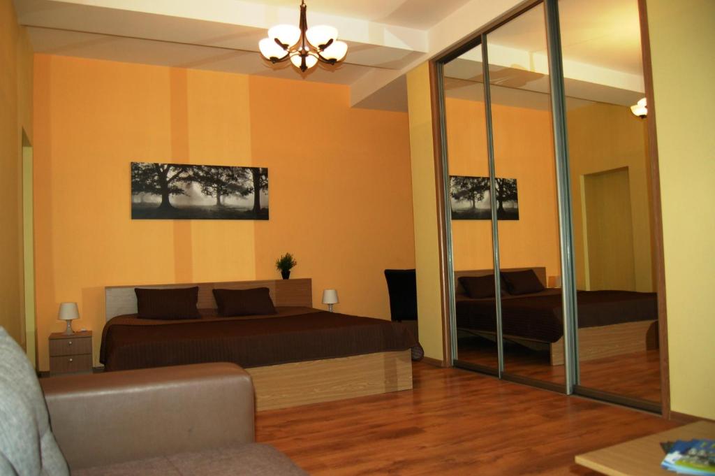 a bedroom with a bed and a couch and a mirror at Valdemaras Apartment 91 in Rīga