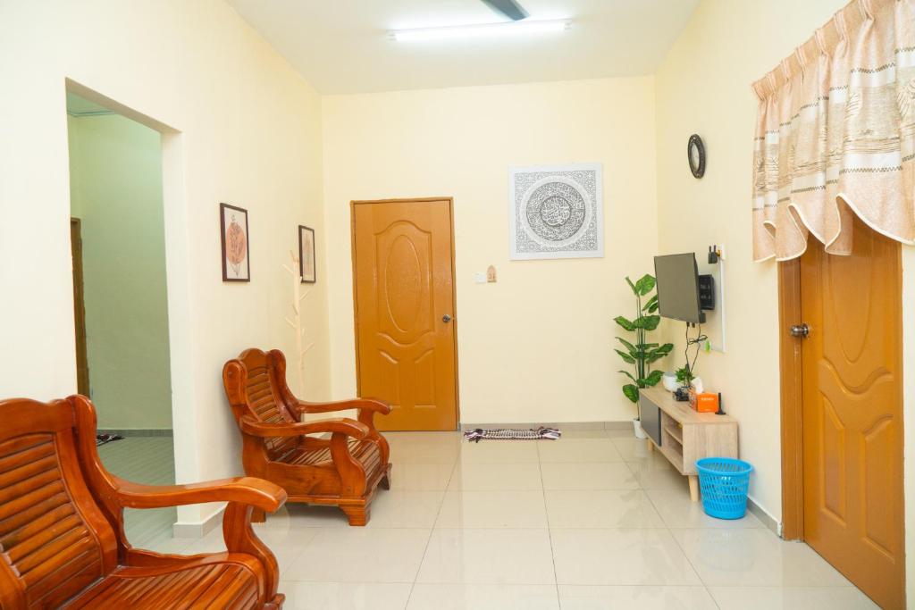 sala de estar con 2 sillas y TV en Adorable 2-bedroom home with Wi-Fi, Netflix and BBQ grill, en Rembau