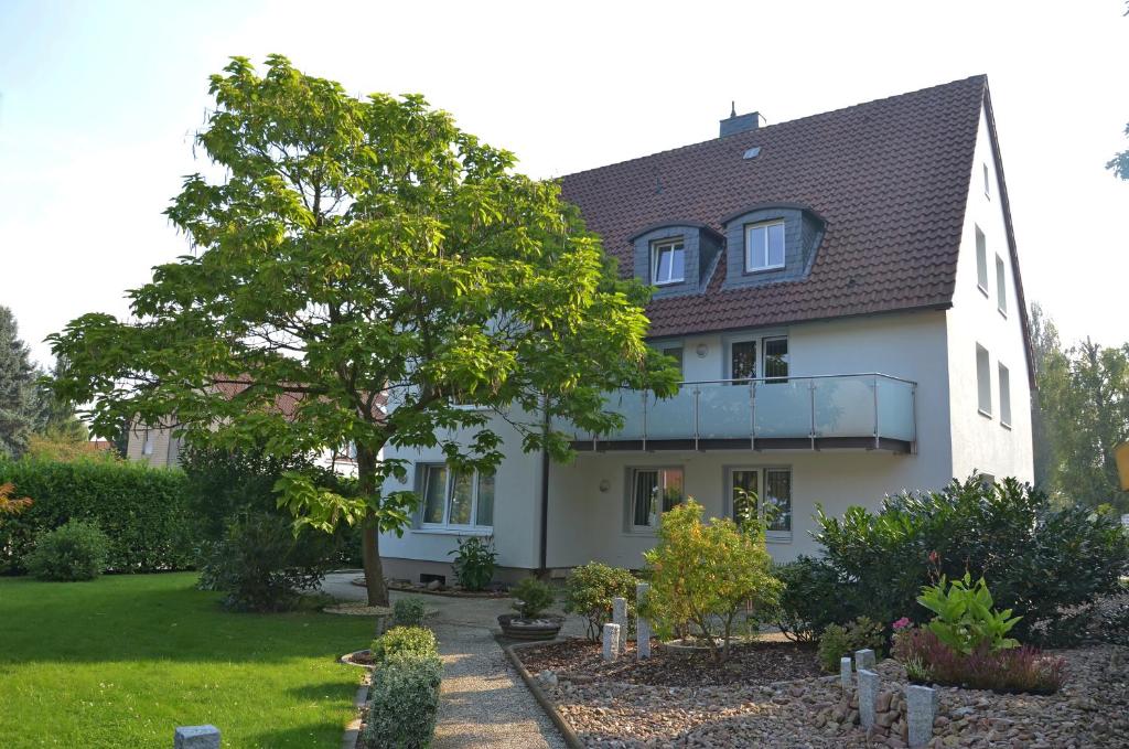 a white house with a tree in the yard at Parkhotel Stadthagen in Stadthagen