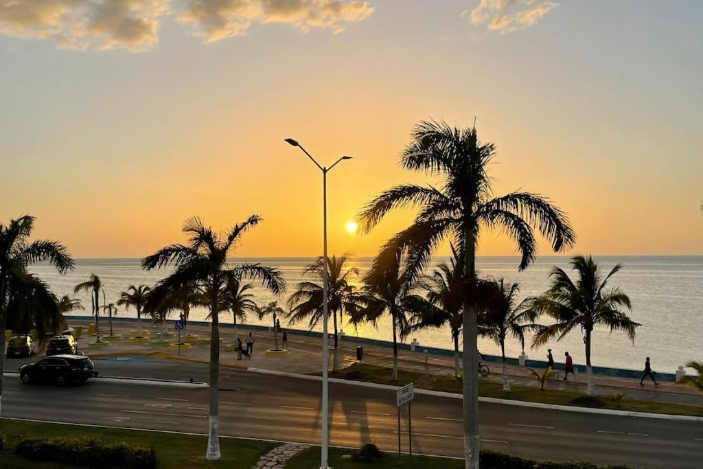 - une rue avec des palmiers et l'océan au coucher du soleil dans l'établissement CASA OCASO - Your home away from home, à Campeche