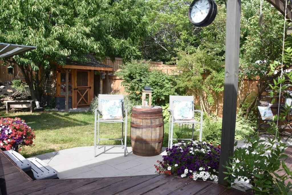 d'une terrasse avec 2 chaises, un tonneau et une horloge. dans l'établissement Cozy Grimsby Suite w/ hot tub & high-speed wifi, à Grimsby