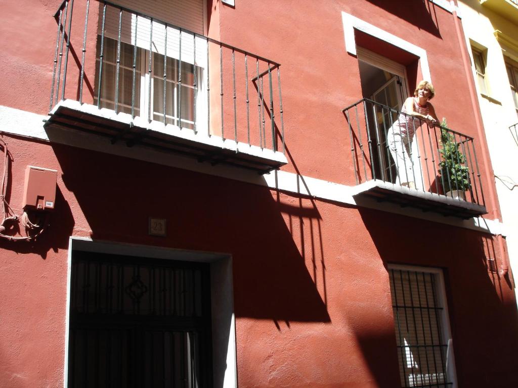 un hombre parado en un balcón de un edificio rojo en La Alcandora, en Granada