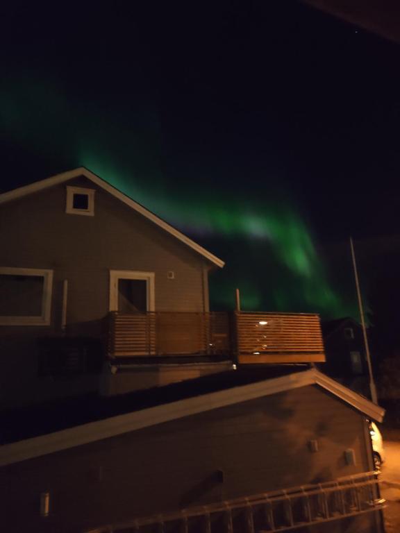 ein Haus mit den grünen Nordlichtern am Himmel in der Unterkunft FeelHome 2 bedrooms apartment Vidarsveg in Tromsø