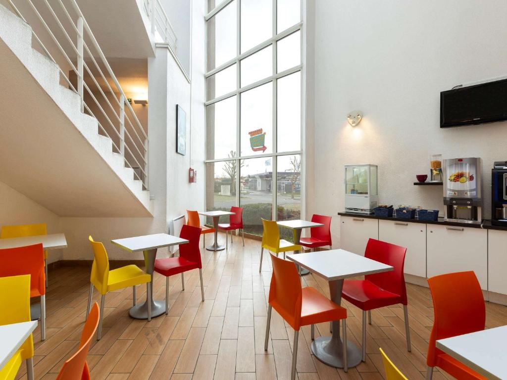 ein Restaurant mit Tischen und Stühlen in einem Zimmer in der Unterkunft Hôtel F1 Reims Tinqueux in Reims