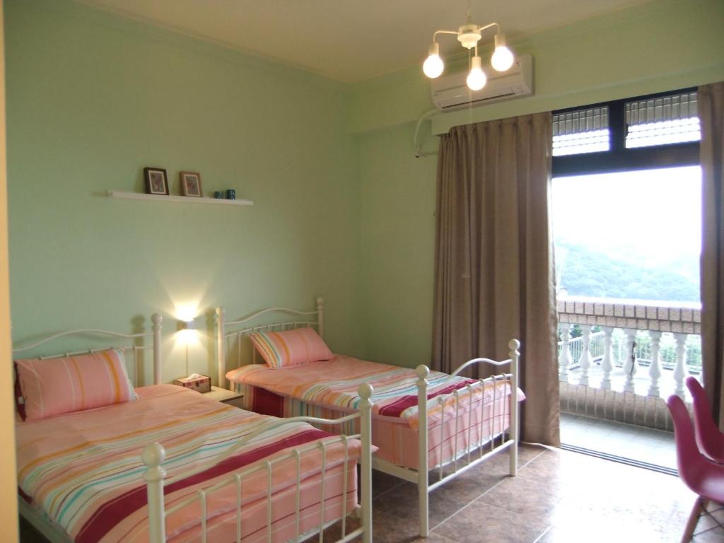 a bedroom with two beds and a balcony at Jiufen Hui Ming Homestay in Jiufen