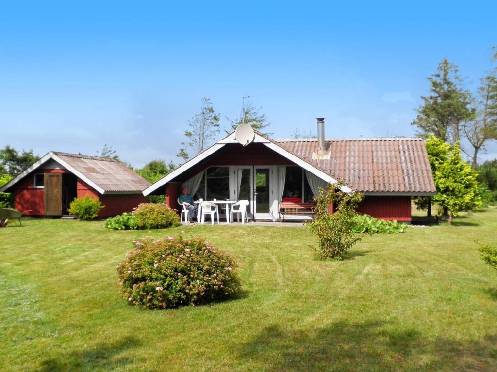 ein rotes Haus mit einem Tisch und Stühlen im Hof in der Unterkunft 5 person holiday home in Ulfborg in Ulfborg