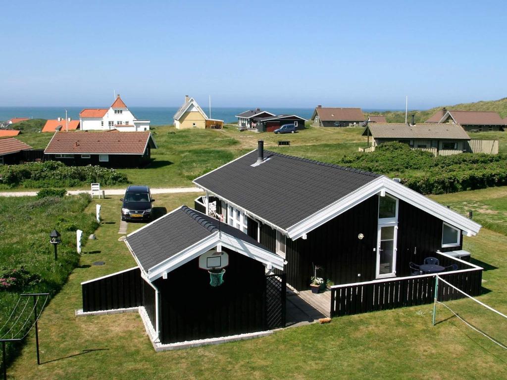 Two-Bedroom Holiday home in Hjørring 1 في لونستروب: منزل أسود مع المحيط في الخلفية