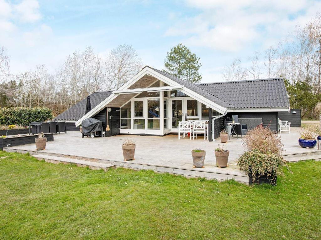 a black house with a deck and a patio at 10 person holiday home in Stege in Stege