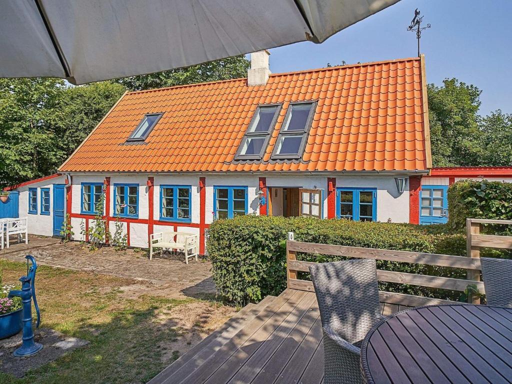 a house with an orange roof with a table and an umbrella at Holiday home Aakirkeby XXXIV in Vester Sømarken