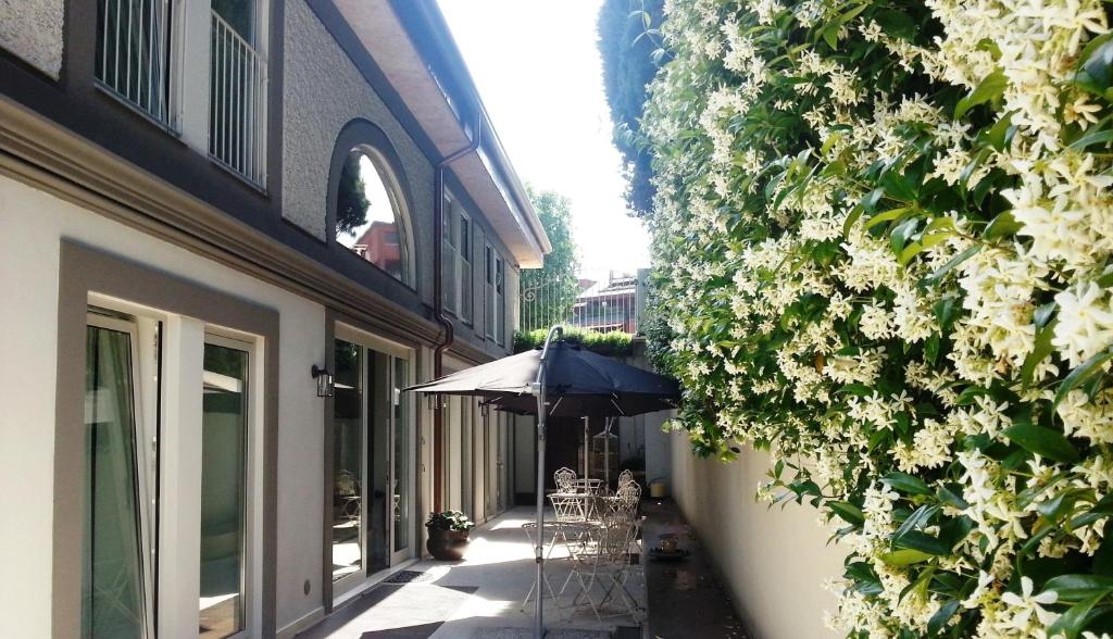 Corte Merighi Charming Rooms في فيرونا: فناء فيه مظلة وطاولات وكراسي