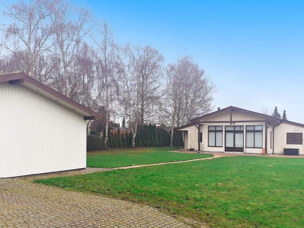 une maison avec une cour verdoyante à côté d'un bâtiment dans l'établissement 6 person holiday home in Kirke Hyllinge, à Kirke-Hyllinge