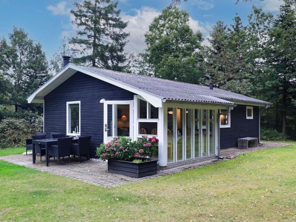 un pequeño cobertizo azul con mesa y sillas en 5 person holiday home in H jslev, en Højslev