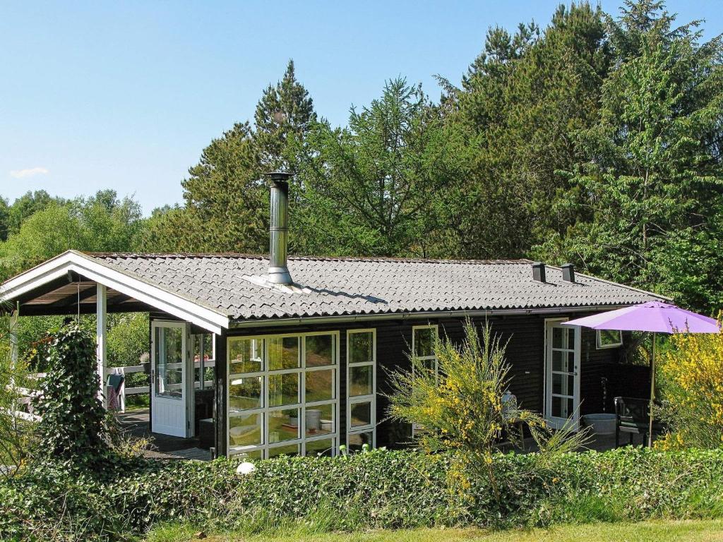 a small black house with a roof and an umbrella at 4 person holiday home in H jslev in Højslev
