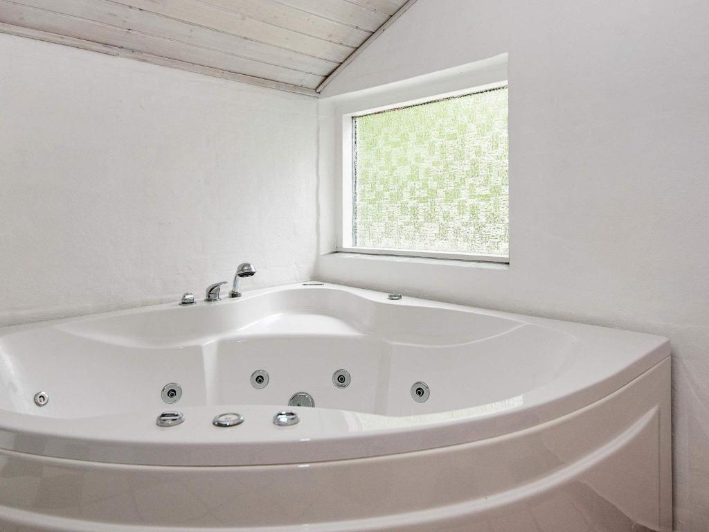 a white bath tub in a bathroom with a window at Four-Bedroom Holiday home in Glesborg 2 in Glesborg