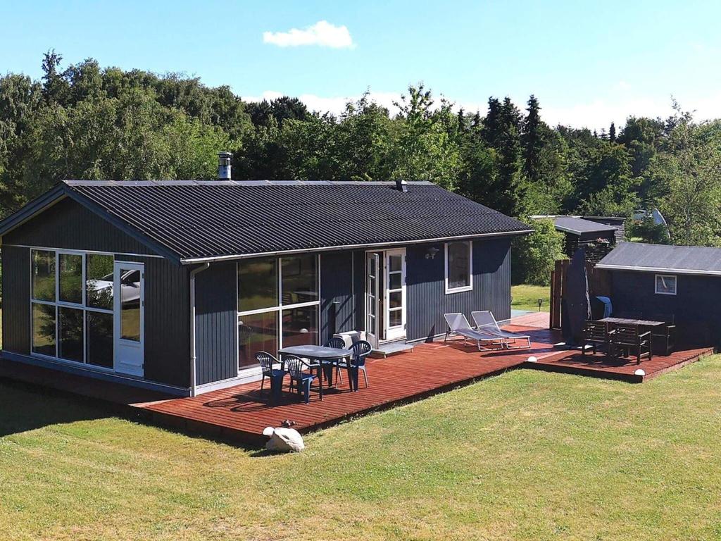 Cette petite maison dispose d'une terrasse avec une table et des chaises. dans l'établissement 6 person holiday home in Nibe, à Nibe