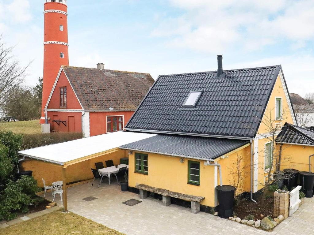 uma casa amarela com um farol ao fundo em Holiday home Læsø XLI em Læsø