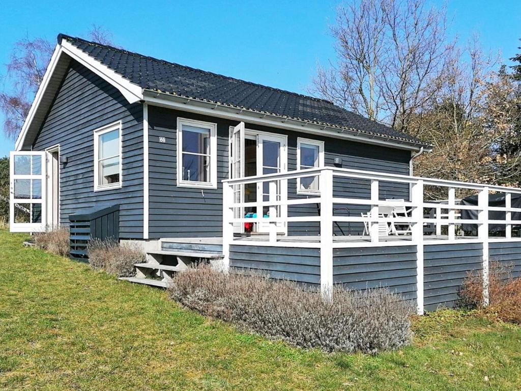 une maison bleue avec une terrasse couverte et une balustrade blanche dans l'établissement 5 person holiday home in Vordingborg, à Vordingborg