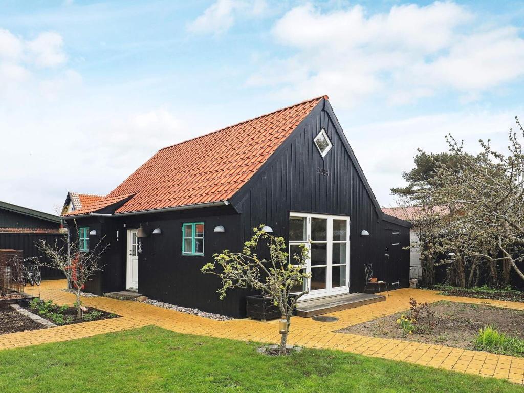 une maison noire avec un toit rouge dans l'établissement 4 star holiday home in Skagen, à Skagen