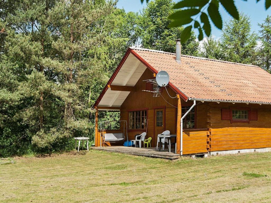 una piccola casa in legno con portico e sedie di 6 person holiday home in rsted a Ørsted