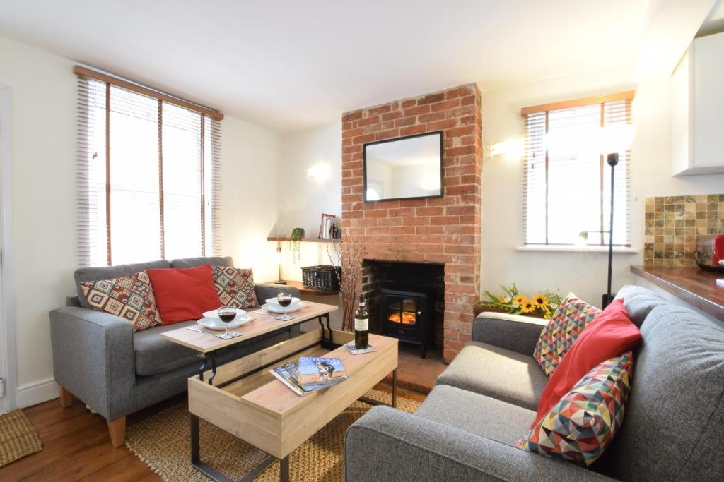 a living room with two couches and a fireplace at 1 Tailors Cottage, Woodbridge in Woodbridge