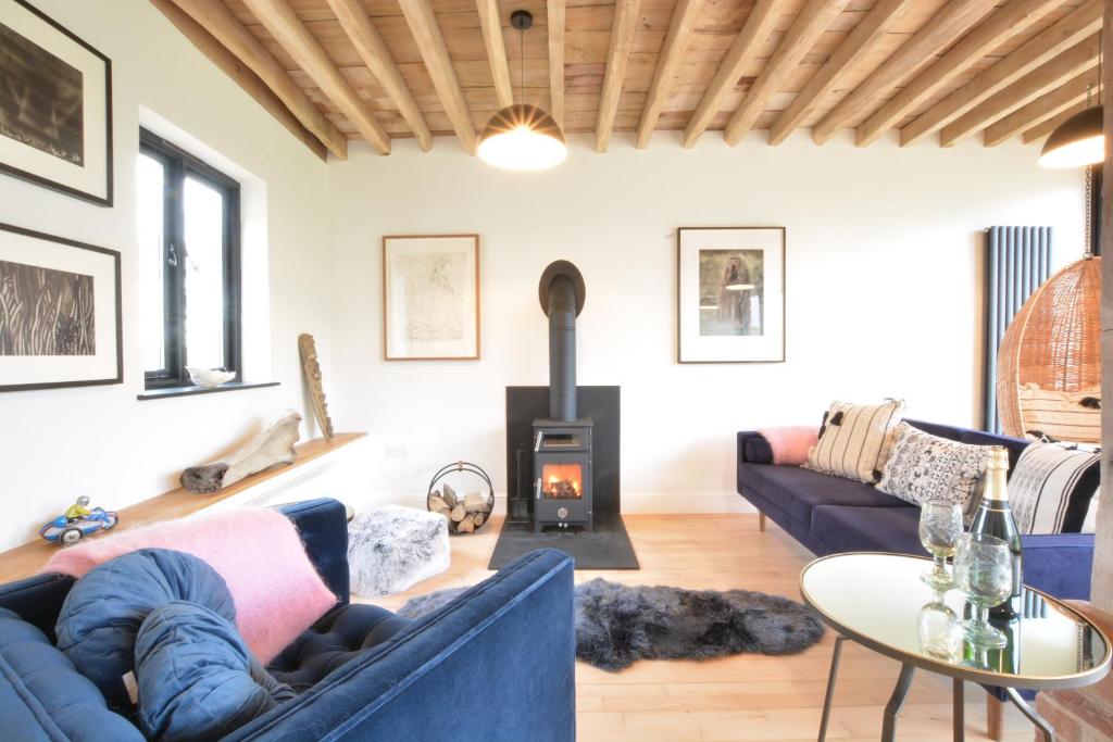 a living room with a blue couch and a wood stove at Fishpond House, Sotherton in Sotherton