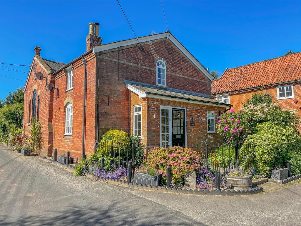 a brick house with flowers in front of it at Chapel Cottage, Newbourne in Newbourn