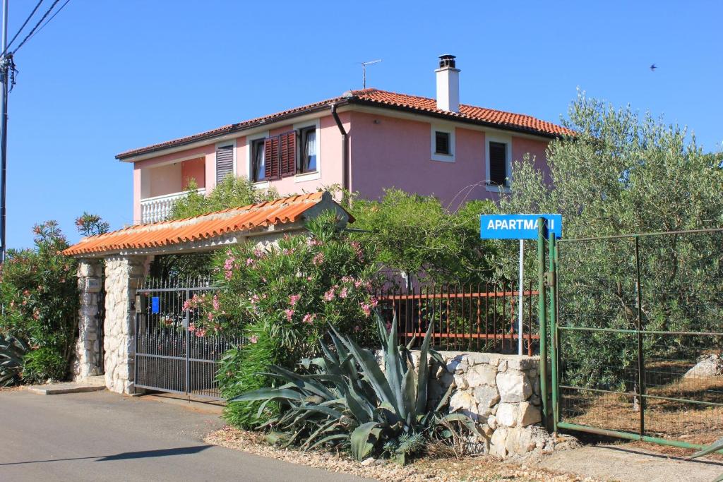 a house with a fence and a street sign in front at Apartments with a parking space Punta kriza, Cres - 383 in Punta Križa