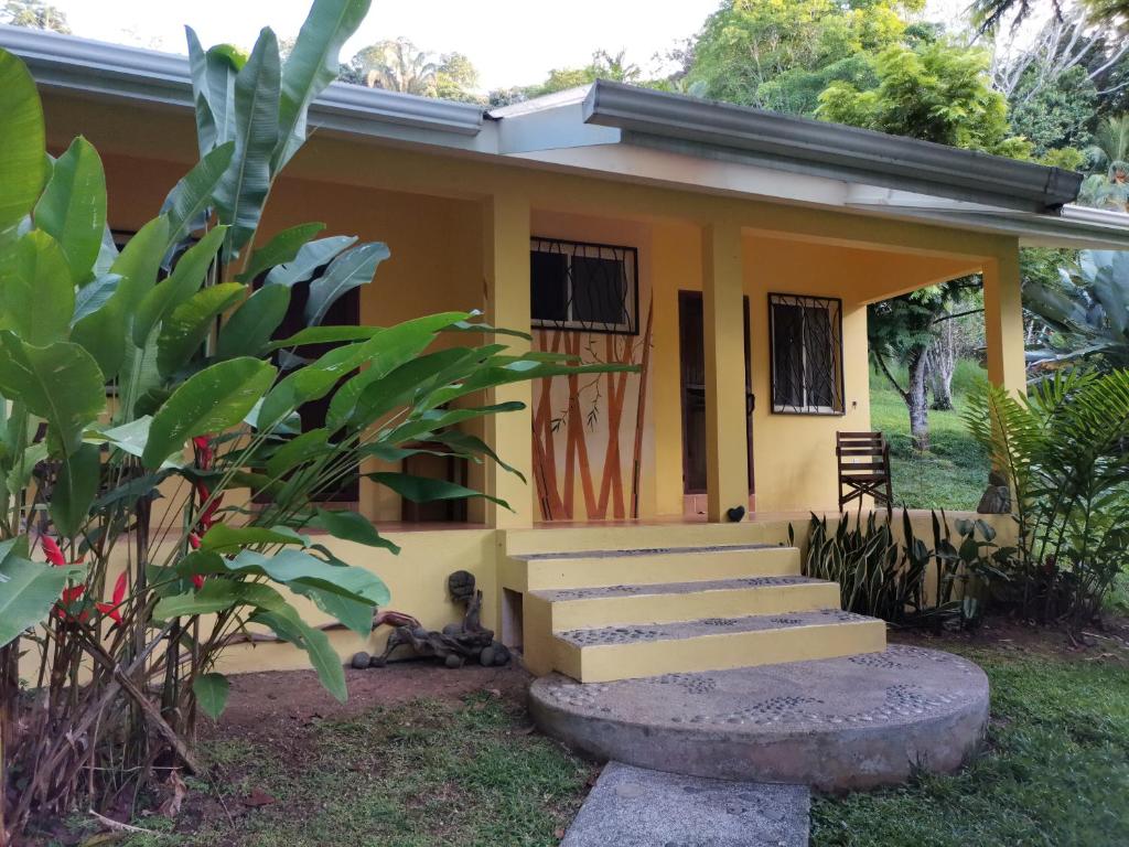 una piccola casa gialla con scale di fronte di Mira Olas Cabins a Pavones
