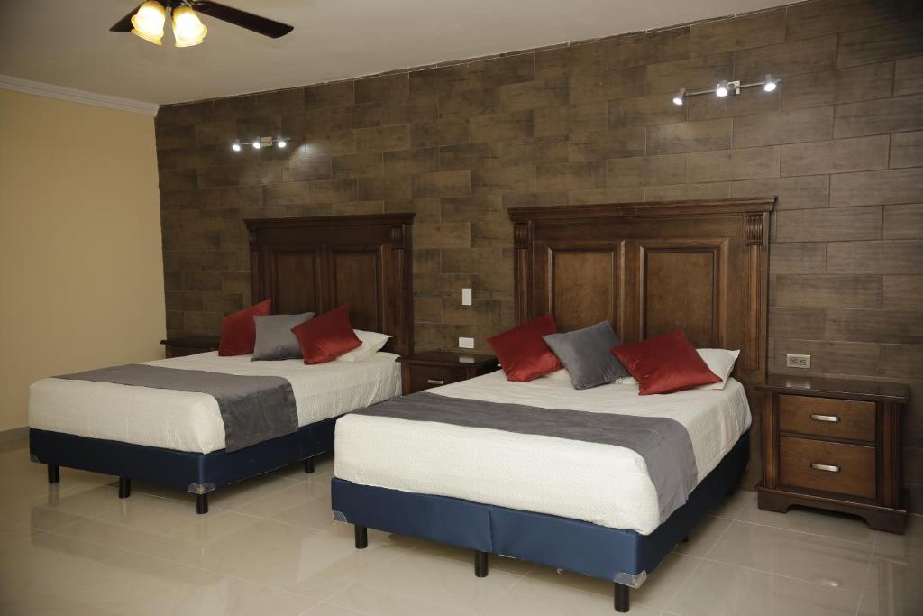1 dormitorio con 2 camas y almohadas rojas en Hotel Posada Santa Fe en Sabinas