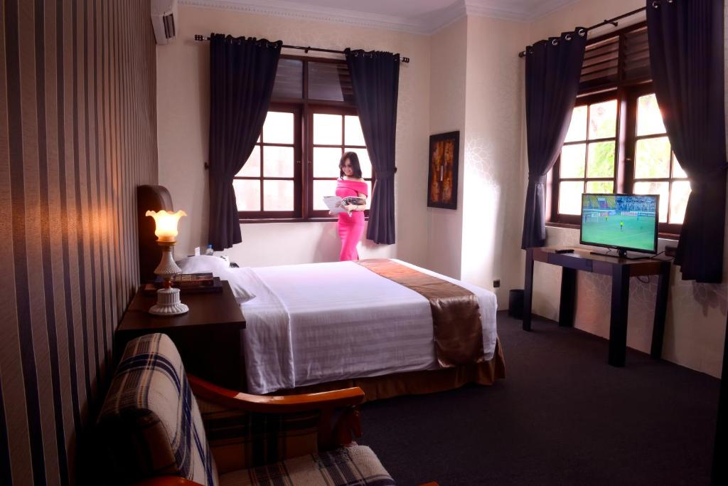 a girl in a pink outfit standing in a hotel room at DS Colive Sinabung in Candi