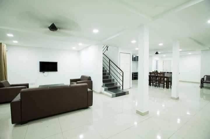 sala de estar con sofá y TV en la pared en Jack Guest House KB 5 Rooms 4 Toilets - Max 20 pax en Kota Bharu
