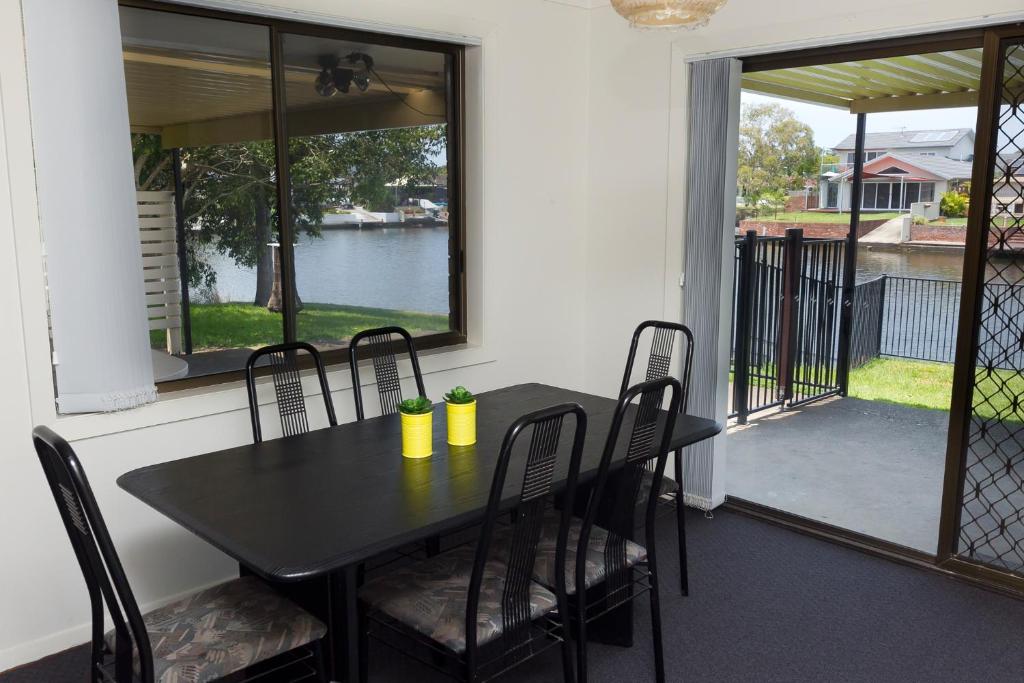 a black table and chairs on a screened in porch at LAKE HOUSE ON ELOUERA in Forster